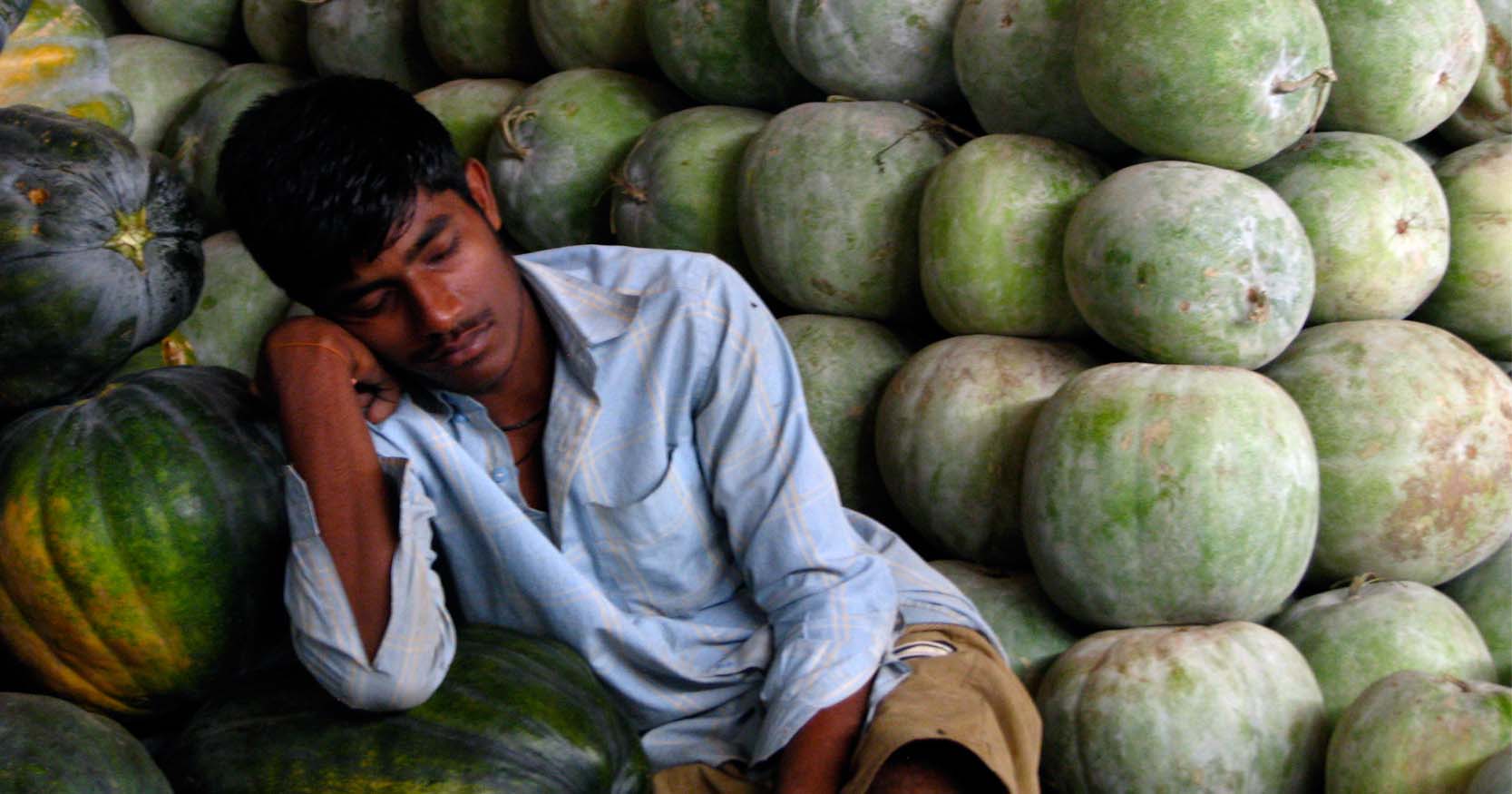 un giovane indiano dorme sopra delle zucche accatastate